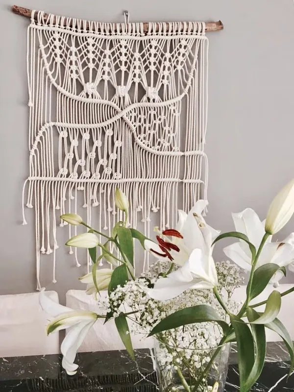Tapeçaria de macramê com franjas decorada com flores